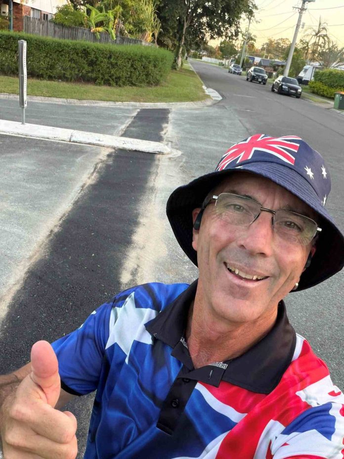 Man making the thumbs up gesture stands in front of a road which has recently had a pothole filled