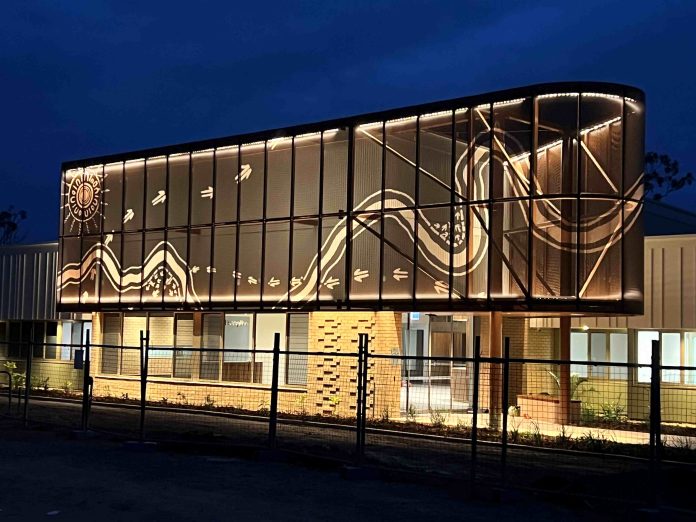 A two-storey brick building with First Nations art wrapping the second level. Construction fencing is in front of the building.